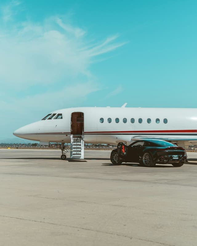 Jet privé sur le tarmac, voiture de sport garée à l'embarquement